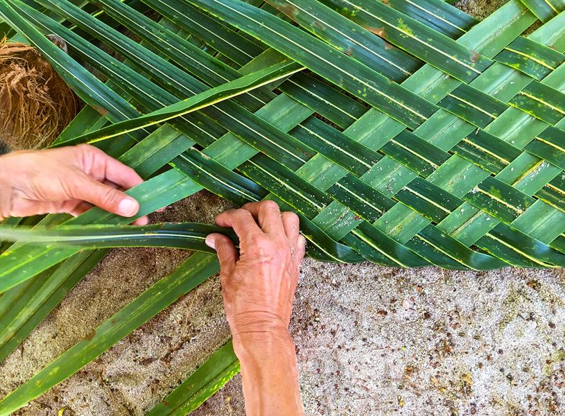Close up of hands weaving palm leaf at Krabei Riel Village, Cambodia