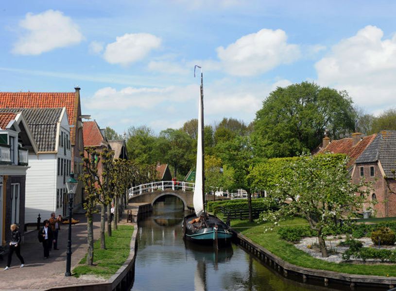 Village scene at Zuiderzee Museum with canal, moored sail boat and houses in Enkhuizen, Netherlands