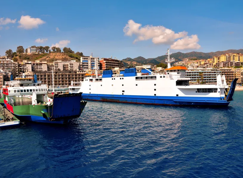 Ferries docked in Messina harbour with colourful buildings and green hills 