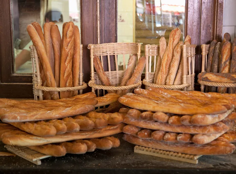 Assorted baguettes stacked in wicker baskets at bakery counter