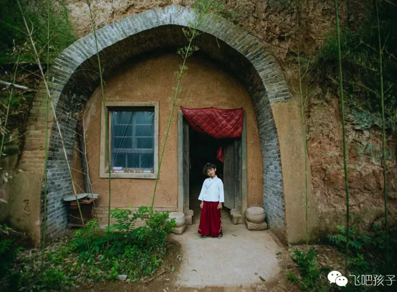 Smiling child standing at the entrance to Yaodong Cave Dwelling, Xian, China