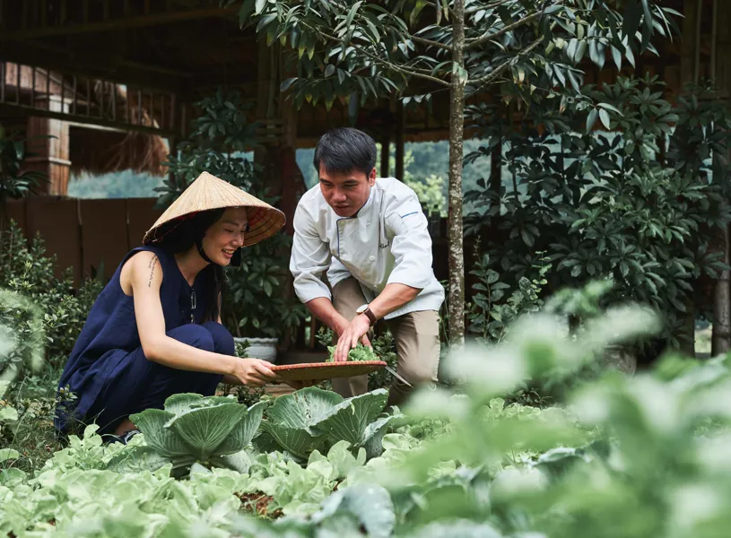 Two persons outdoors surrounded by lush greenery of  Viet Hai Village, HaLong Bay, Vietnam