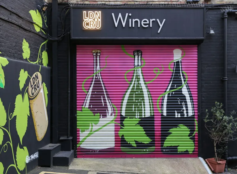 London Cru winery mural with wine bottles and vine leaves on shutter