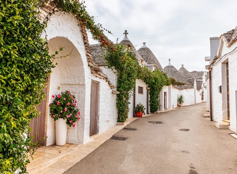 Alberobello street lined with whitewashed trulli houses and greenery