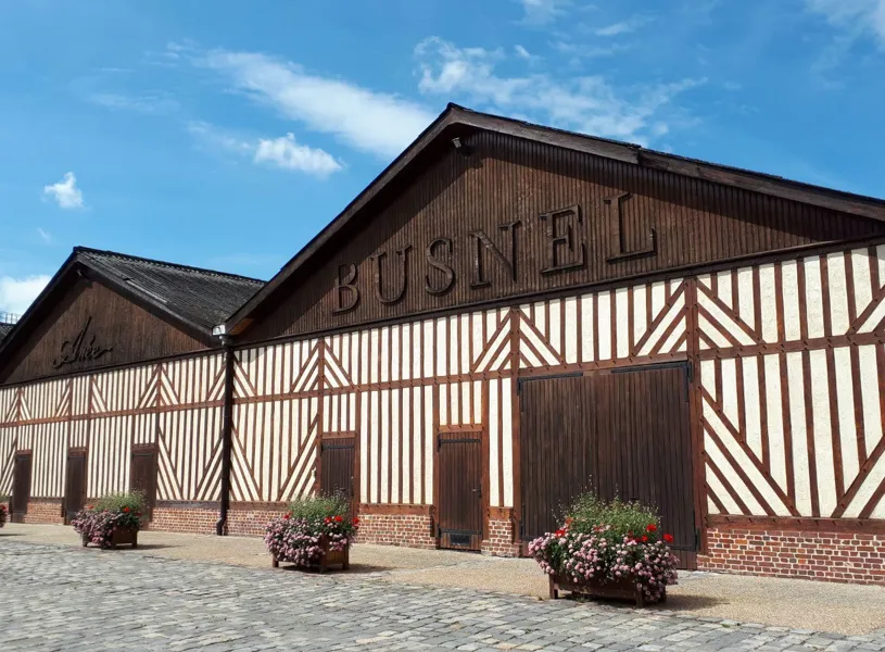 Half-timbered Distillerie Busnel building with gabled roof and flower pots in Normandy, France