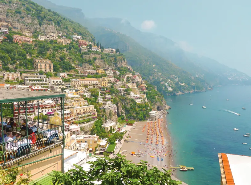 Positano beach with colourful umbrellas and hillside houses along Amalfi Coast
