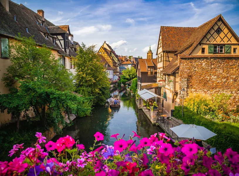 Colmar canal lined with flower, timbered houses and a boat in France