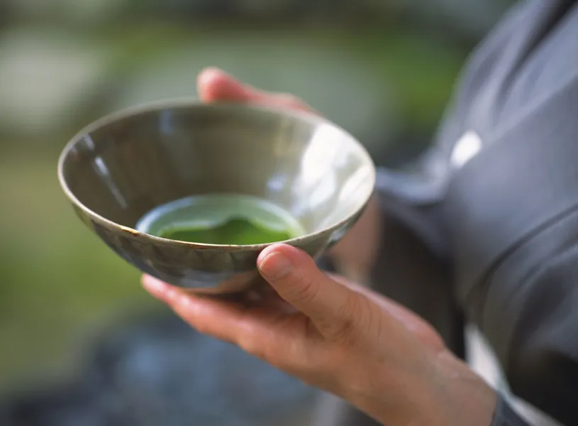 Hands holding a ceramic cup of green tea, Kanazawa, Japan