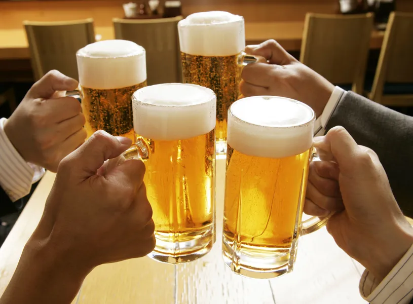 Four hands clinking large mugs of beer at a table, Sapporo, Hokkaido, Japan