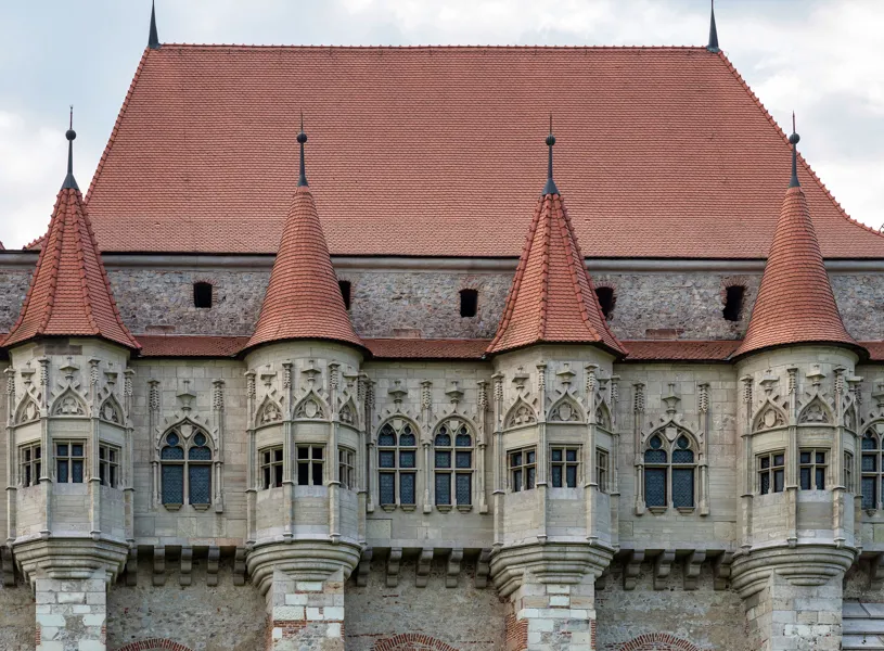 Close-up of Corvin Castle facade with Gothic windows and red tiled roof