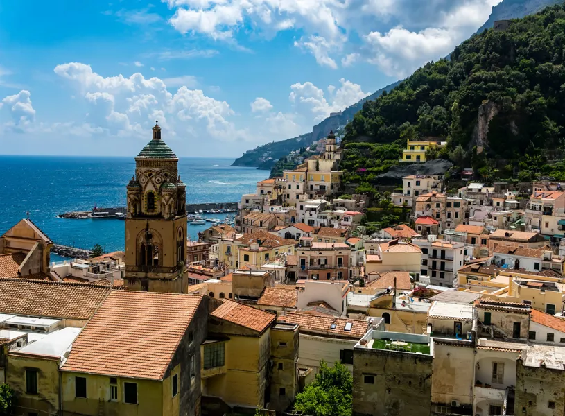 Cathedral of St. Andrea with ornate bell tower overlooking Amalfi rooftops and coastline