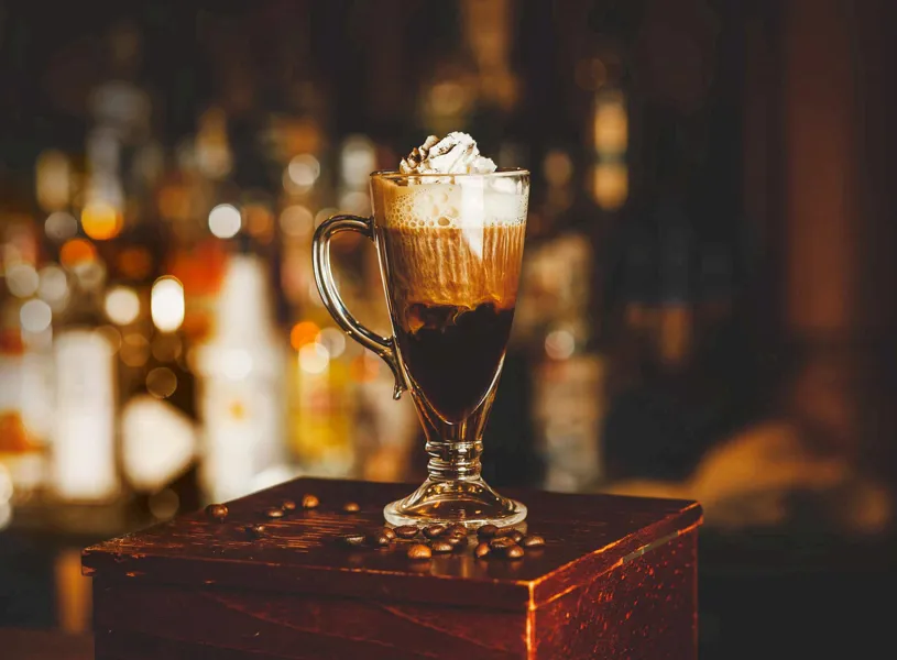 Irish coffee with whipped cream on wooden bar table