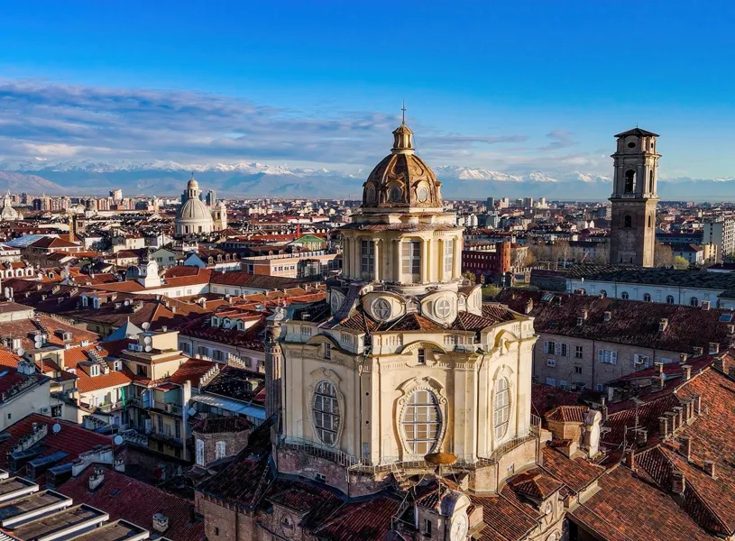 Aerial view of Turin city with Guarini’s dome and historic rooftops framed by snow-capped Alps