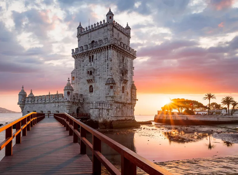 Belem Tower with wooden walkway and calm waterfront at sunset in Lisbon, Portugal