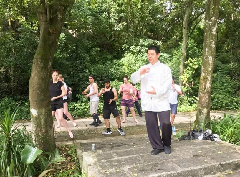 Travellers outdoors at a Tai Chi Class with instructor, China