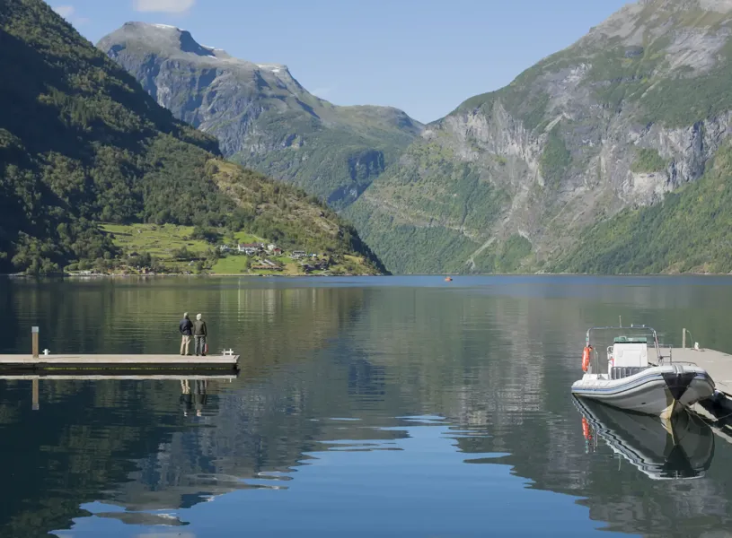 Group of people sitting overlooking Geirangerfjord Western Fjords Norway 