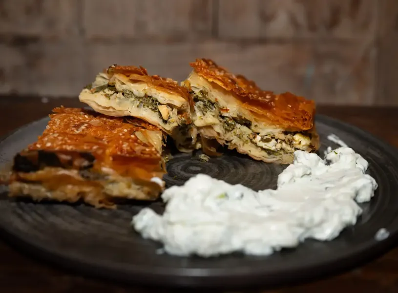 Crispy layered pie slices with herb filling served alongside creamy dip, Delphi, Greece