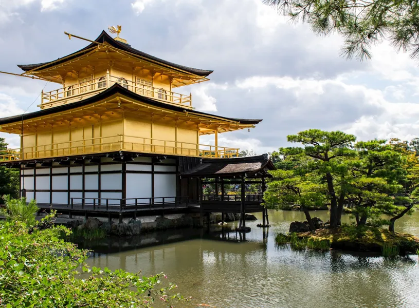Golden Kinkakuji temple reflected in pond surrounded by greenery, Kyoto, Japan 