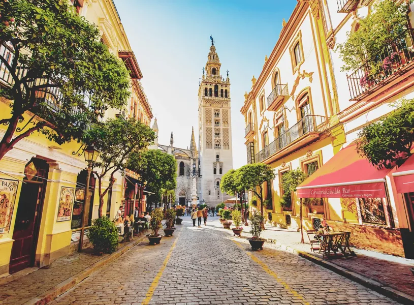 Sunny Seville street and scenic view of Giralda tower, Seville, Spain