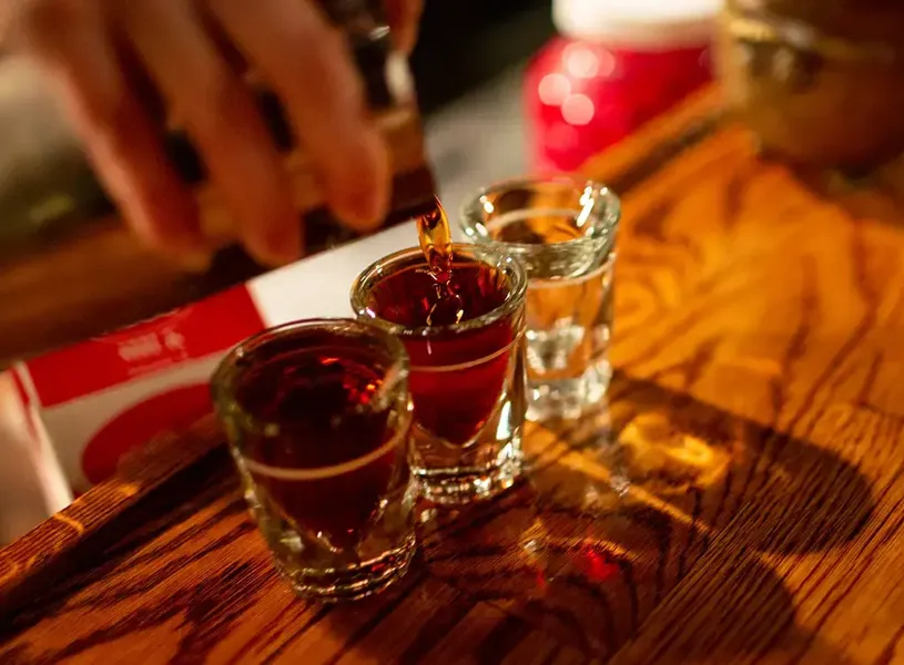 Whiskey Being Poured Into Shot Glasses On Bar